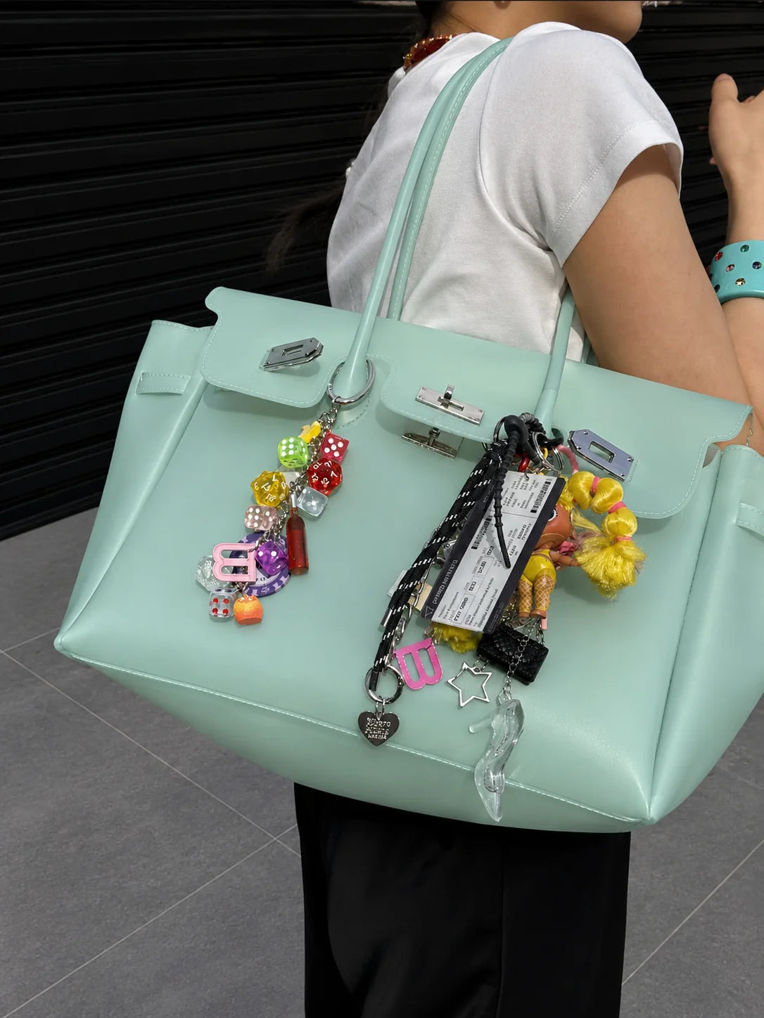 Un sac jelly mint porté à l’épaule, chargé de charms